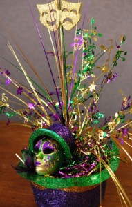DIY Mardi Gras Centerpiece made from an upside down purple, green, and gold hat filled with foil tensil, onion grass, leaf picks, and ornaments.