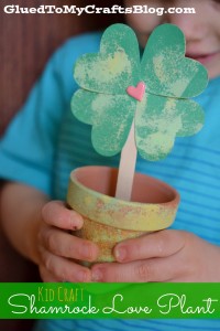 A terra cotta plant is painted and jazzed up to hold a shamrock crafted from four green hearts into a lovely St. Patrick's Day craft.