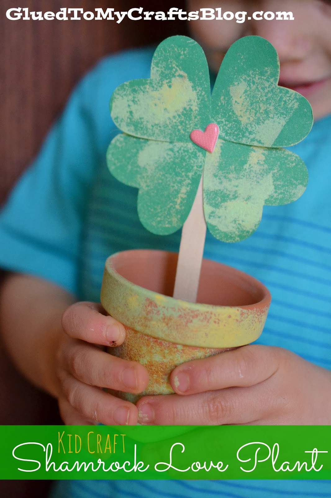 A terra cotta plant is painted and jazzed up to hold a shamrock crafted from four green hearts into a lovely St. Patrick's Day craft.
